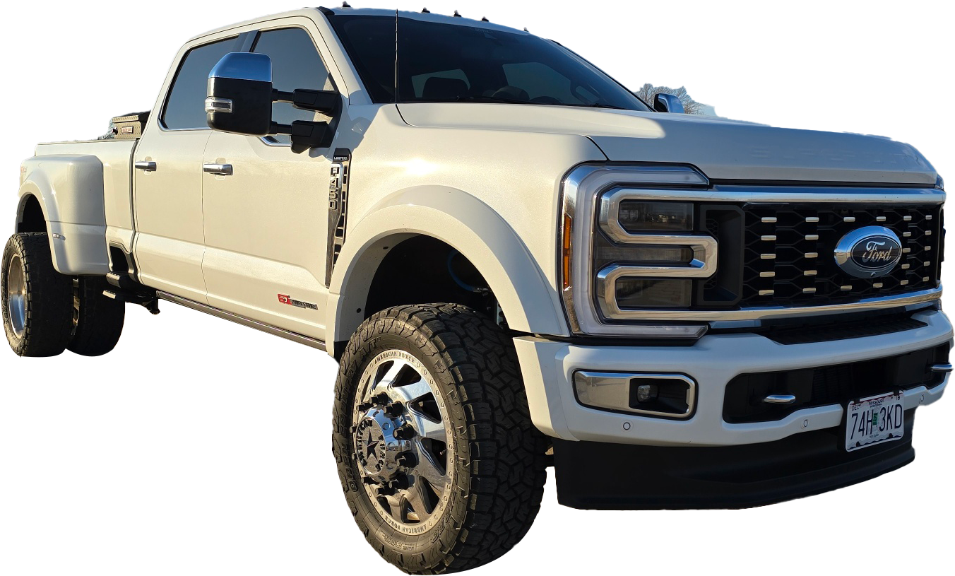 A white truck with large tires is parked.