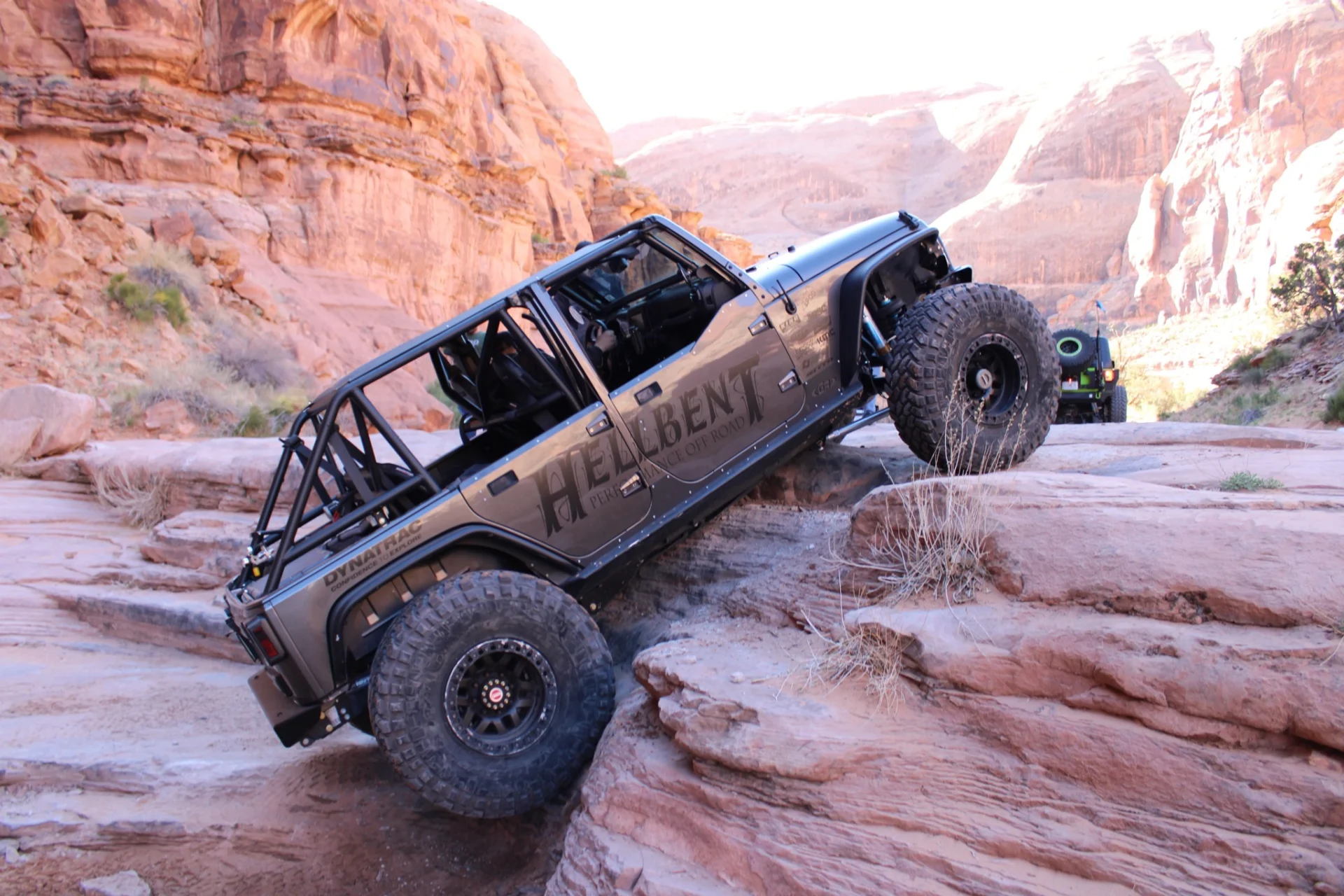 A jeep is driving over some rocks on the side of a mountain.